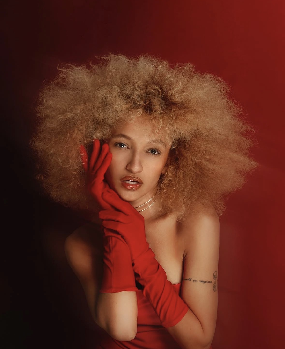 Nalu Rodrigues in a red look against a deep-red studio backdrop.