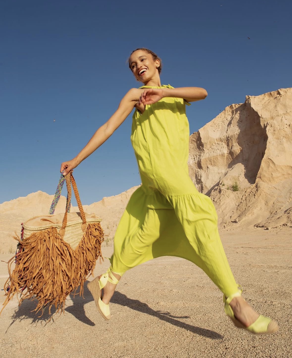 Nalu posing in a lime-green look against a rocky landscape.