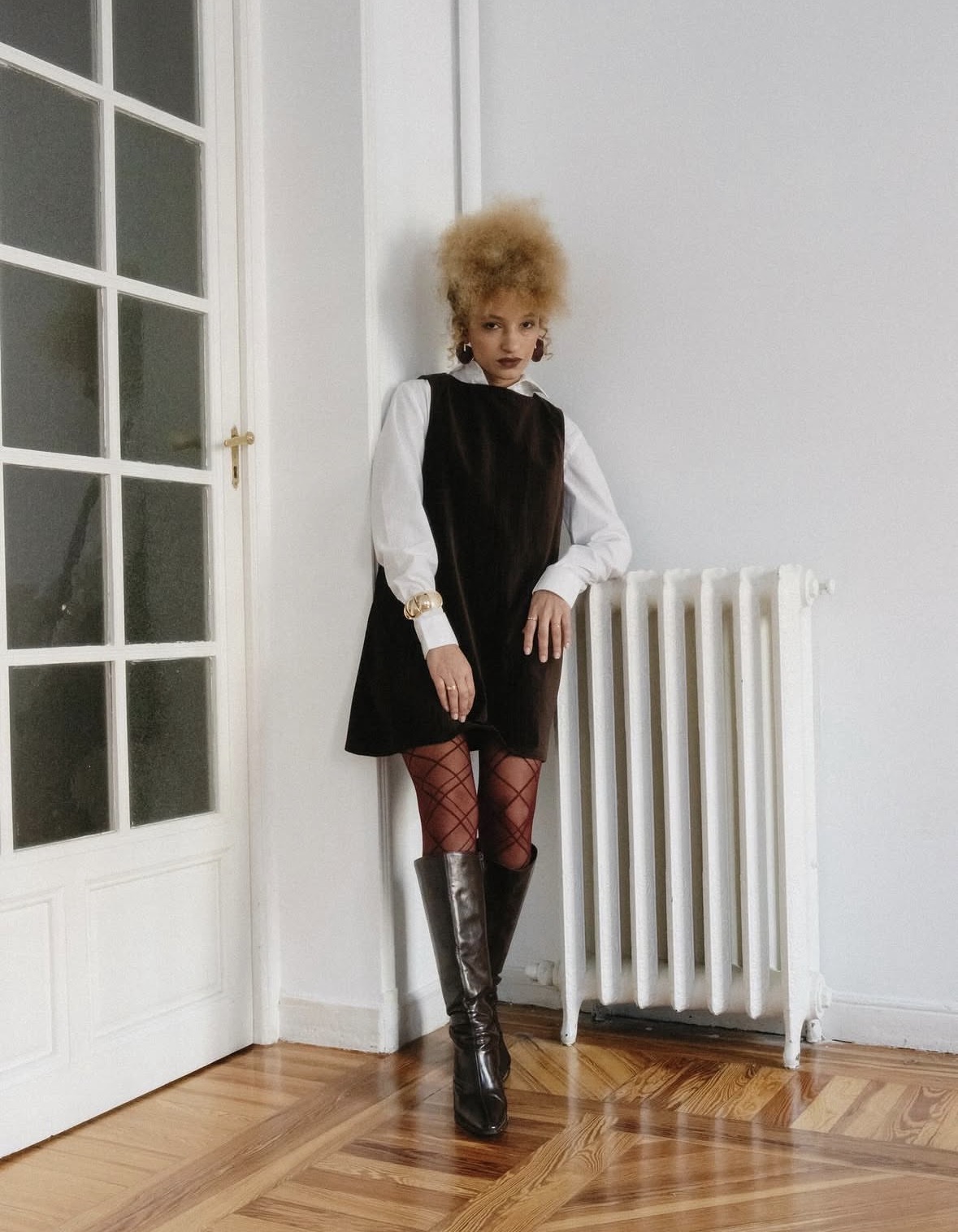 Nalu standing in a black dress over a white blouse in a bright room.