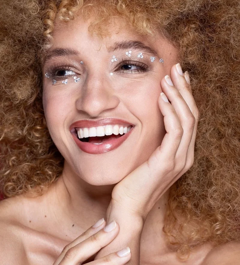 Close portrait of Nalu smiling with her hand against her face.