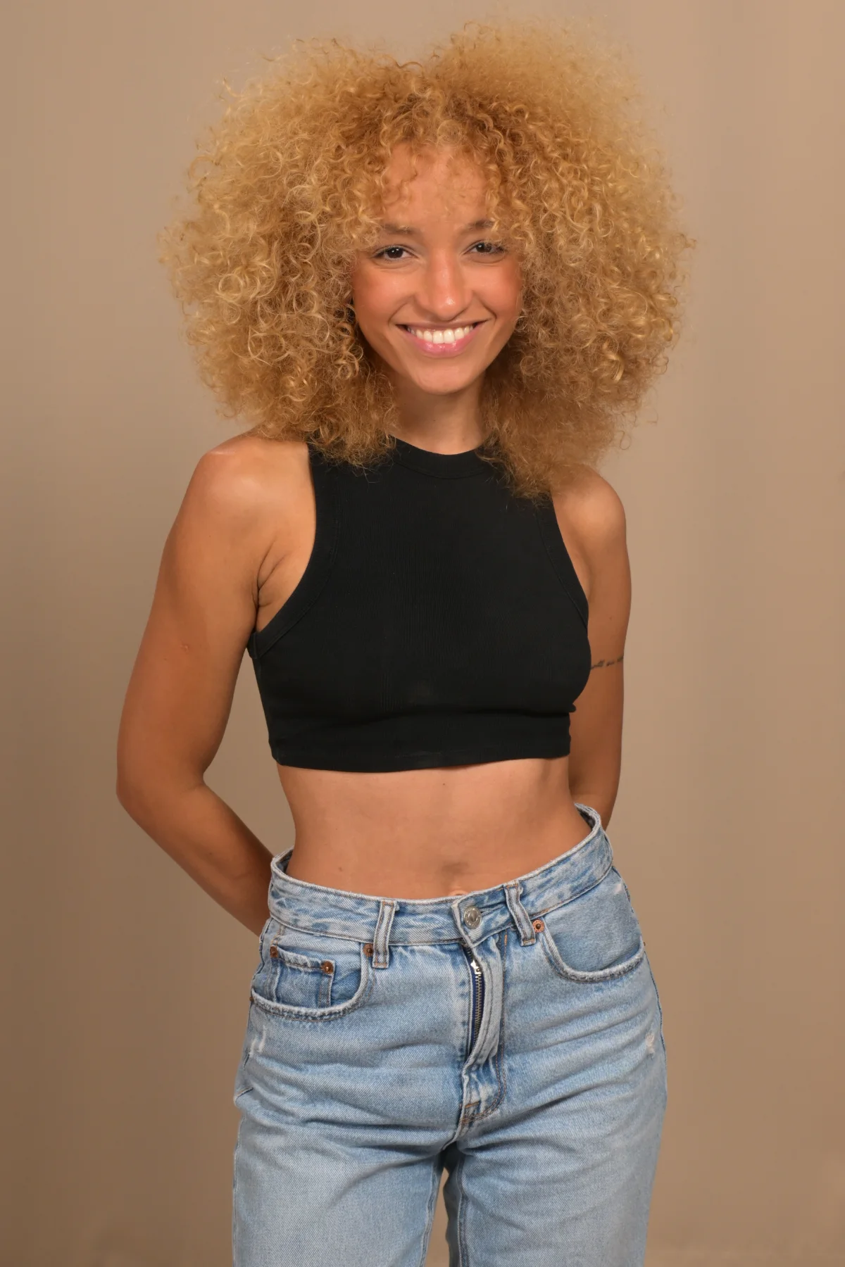 Smiling full-length portrait of Nalu wearing a black top and jeans.